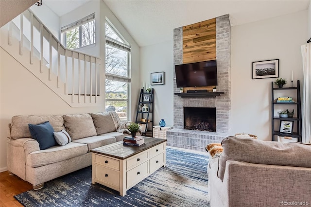 living area featuring a brick fireplace, dark wood finished floors, plenty of natural light, and stairway
