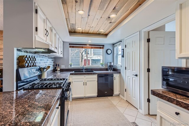 kitchen with a raised ceiling, tile counters, a sink, and black appliances