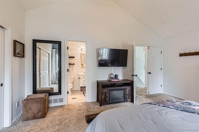 carpeted bedroom featuring high vaulted ceiling and ensuite bathroom