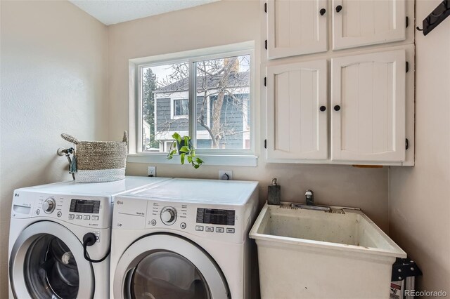 laundry room with cabinet space, a sink, and washing machine and clothes dryer