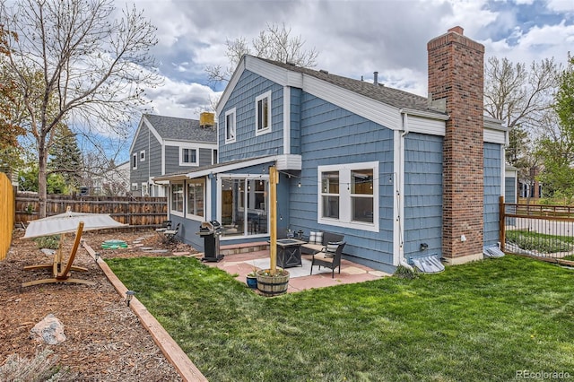 rear view of house with a yard, a patio, a chimney, and a fenced backyard