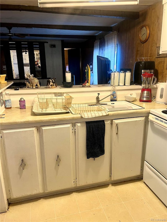 kitchen with wood walls, sink, light tile patterned floors, and white stove