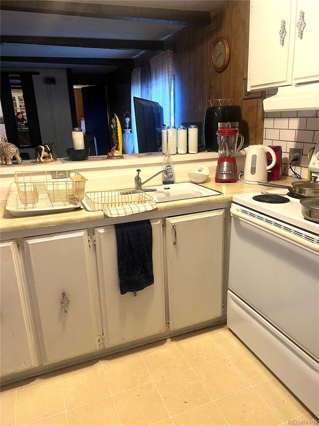 kitchen with tasteful backsplash, sink, light tile patterned flooring, and white range