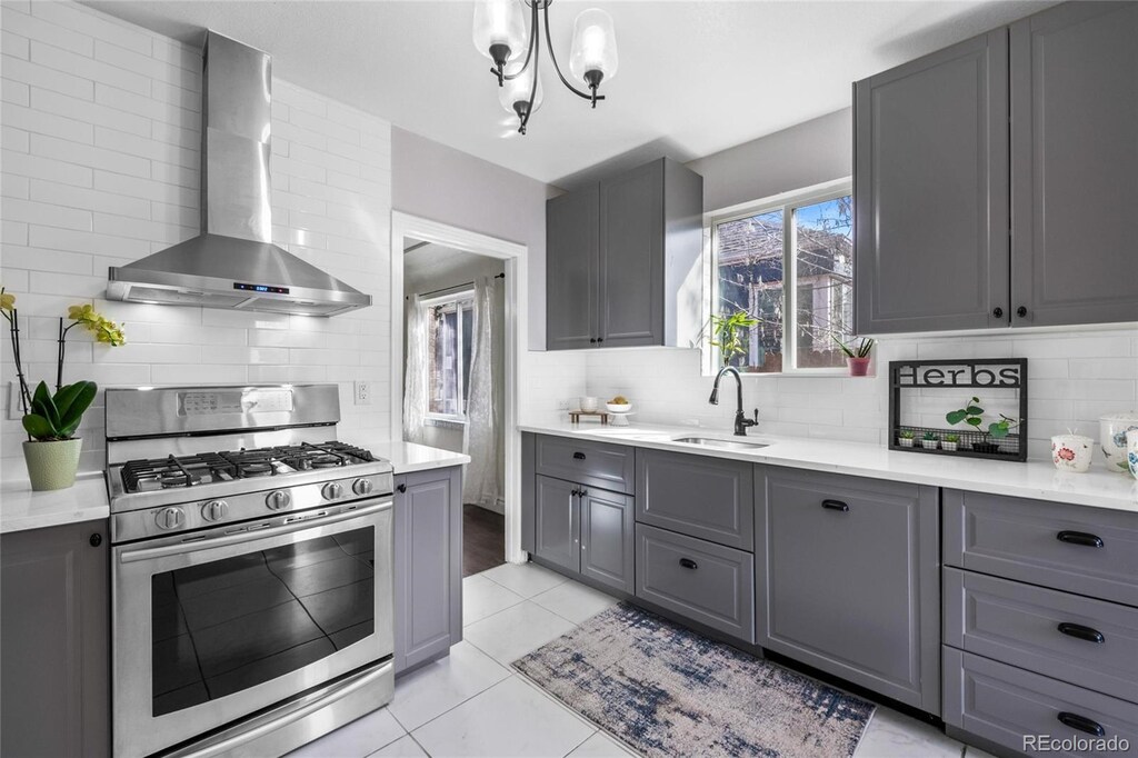 3083 Ash St, Denver, CO 80207 - kitchen featuring gas range, wall chimney exhaust hood, and gray cabinetry