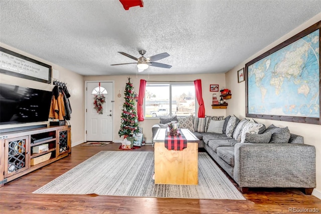 living room featuring ceiling fan, dark hardwood / wood-style flooring, and a textured ceiling