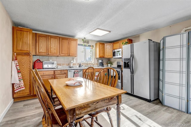 kitchen featuring light wood-type flooring, appliances with stainless steel finishes, and a textured ceiling