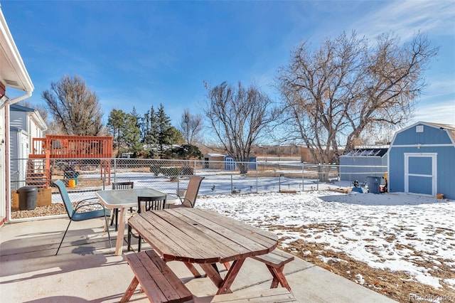 snow covered patio with a storage shed