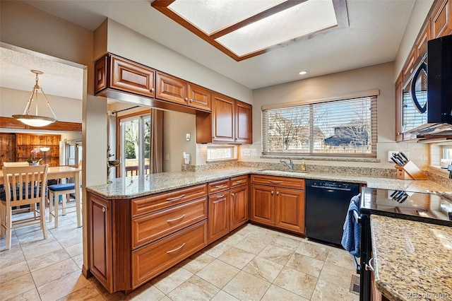 kitchen with light stone countertops, a sink, decorative backsplash, black appliances, and brown cabinets