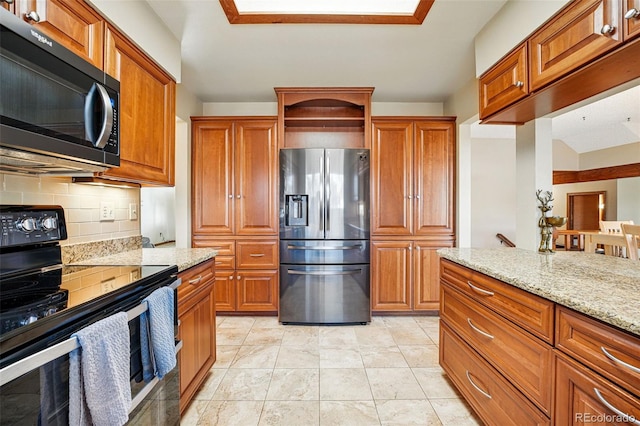 kitchen with light stone counters, brown cabinetry, electric stove, stainless steel fridge, and backsplash