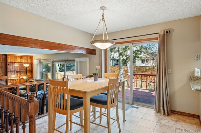 dining space with visible vents, a textured ceiling, and baseboards