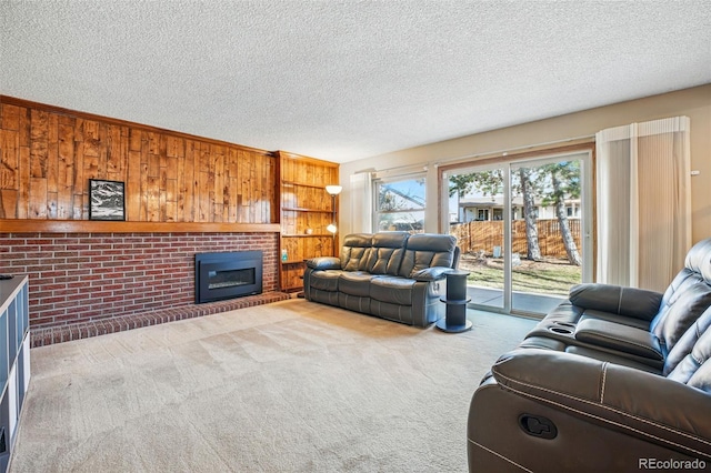 living area featuring a textured ceiling, a brick fireplace, wood walls, and carpet flooring