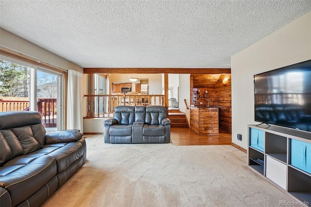 carpeted living area featuring wooden walls, baseboards, and a textured ceiling