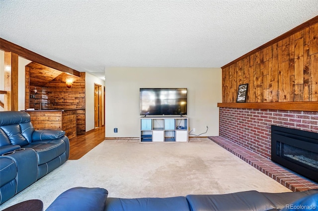 living room featuring wood walls, a brick fireplace, a textured ceiling, and carpet