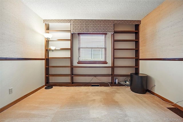 carpeted spare room with baseboards, a textured ceiling, and wallpapered walls