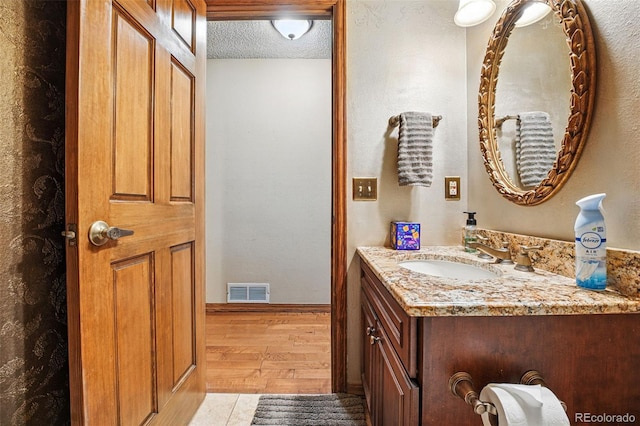 bathroom featuring vanity, wood finished floors, visible vents, and a textured ceiling