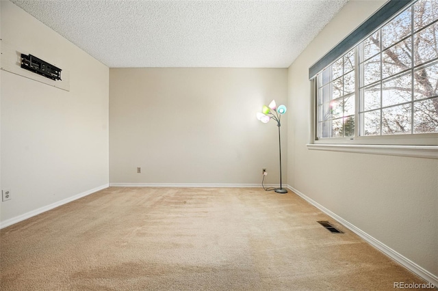 unfurnished room featuring visible vents, baseboards, light colored carpet, and a textured ceiling