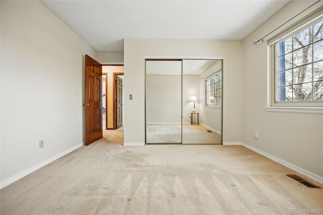 unfurnished bedroom featuring visible vents, multiple windows, baseboards, and carpet floors