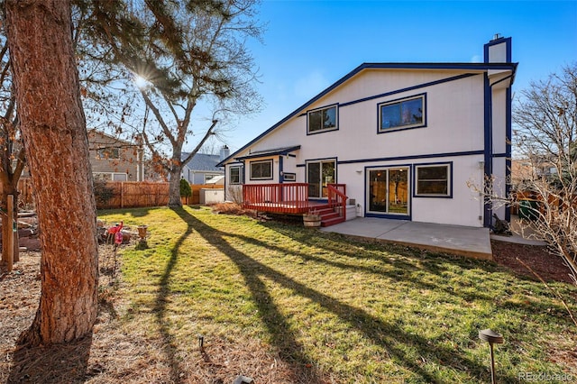 rear view of property with a patio, fence, a chimney, a deck, and a lawn