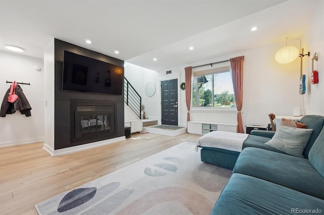 living room featuring wood finished floors, baseboards, stairway, recessed lighting, and a multi sided fireplace