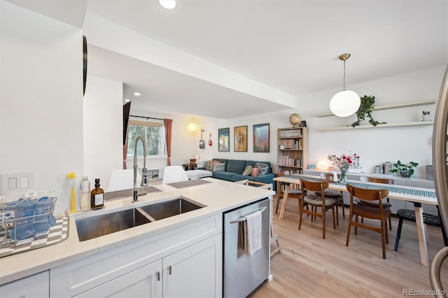 kitchen with white cabinets, a sink, dishwasher, light countertops, and light wood-type flooring