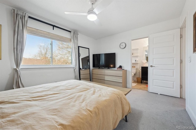 carpeted bedroom with ensuite bathroom and ceiling fan
