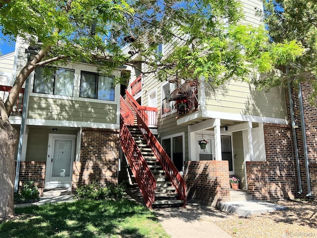 rear view of property featuring brick siding and stairs