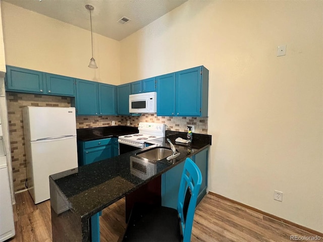 kitchen featuring white appliances, visible vents, a peninsula, blue cabinets, and backsplash