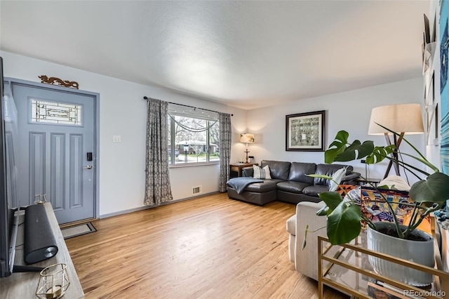 living room with baseboards, visible vents, a wealth of natural light, and light wood finished floors