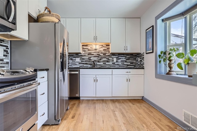 kitchen featuring white cabinets, stainless steel appliances, dark countertops, and visible vents