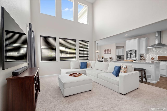 living room featuring light colored carpet, a high ceiling, and an inviting chandelier