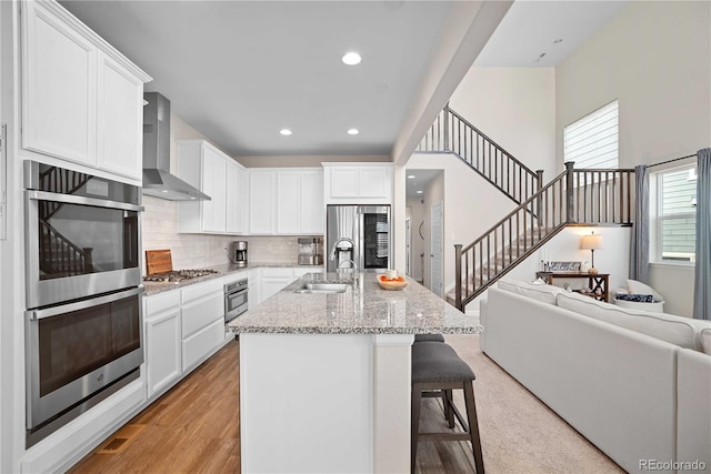 kitchen featuring sink, white cabinets, and wall chimney range hood