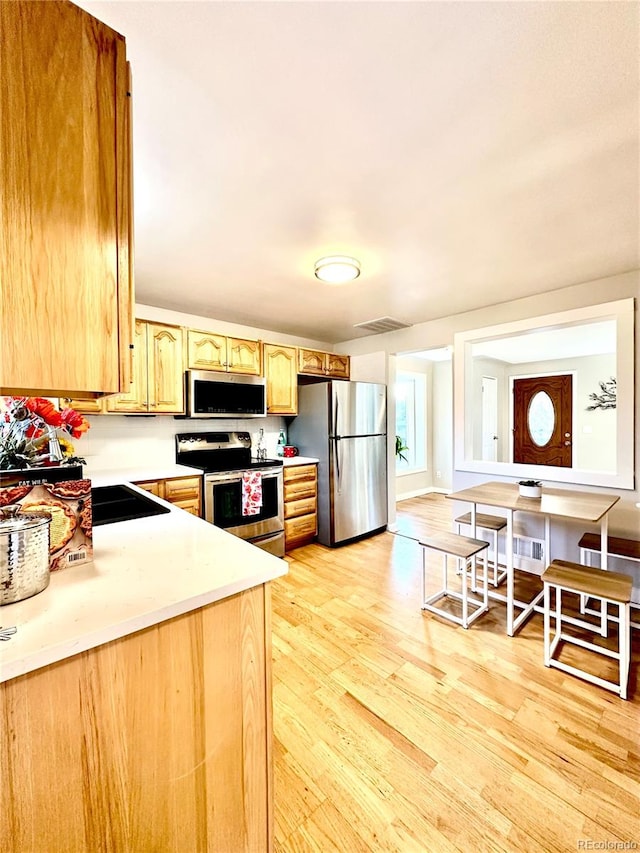 kitchen with appliances with stainless steel finishes, light wood-type flooring, and light brown cabinets