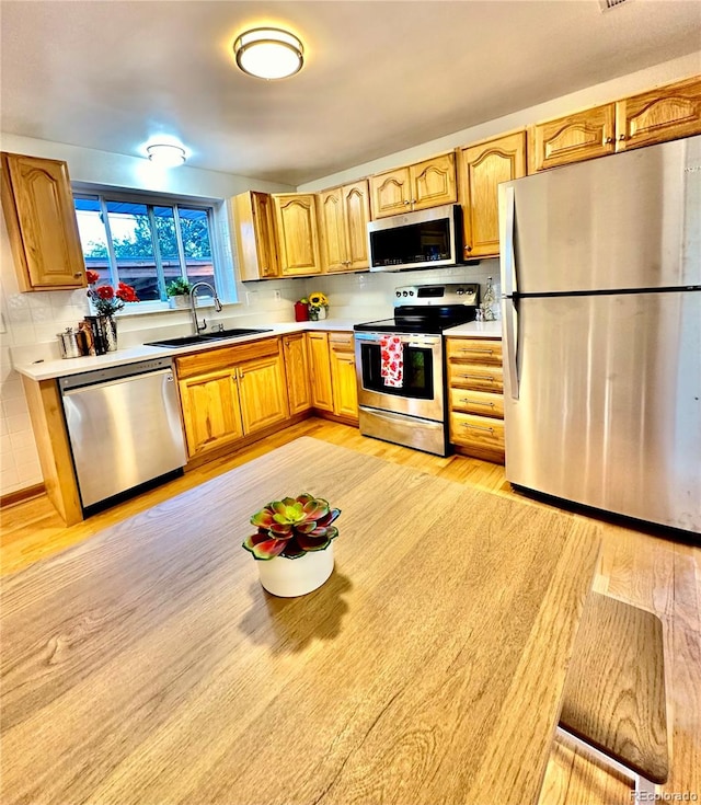 kitchen with light hardwood / wood-style floors, appliances with stainless steel finishes, and sink