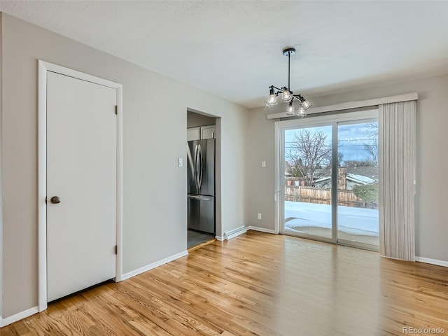 unfurnished dining area featuring light hardwood / wood-style floors and a chandelier