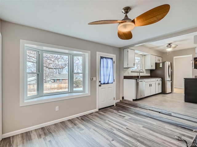 kitchen featuring sink, light hardwood / wood-style flooring, ceiling fan, white cabinetry, and stainless steel appliances