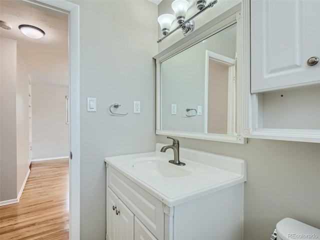 bathroom featuring vanity, hardwood / wood-style flooring, and toilet