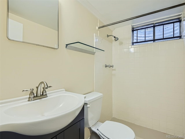 bathroom with tiled shower, vanity, toilet, and ornamental molding