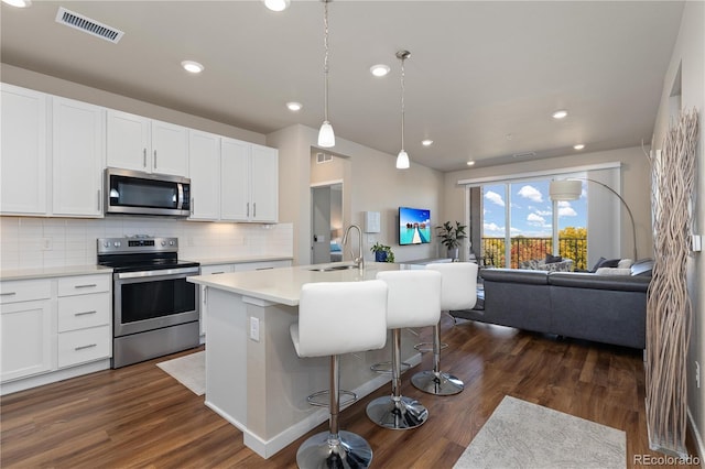 kitchen featuring white cabinetry, stainless steel appliances, dark hardwood / wood-style flooring, and an island with sink