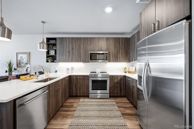 kitchen with sink, hanging light fixtures, dark hardwood / wood-style floors, kitchen peninsula, and stainless steel appliances