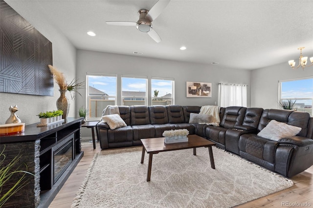 living room with light hardwood / wood-style flooring and ceiling fan with notable chandelier