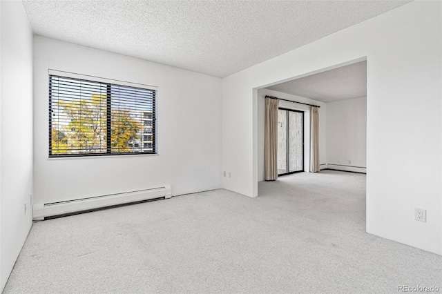 unfurnished room with a wealth of natural light, a textured ceiling, and a baseboard heating unit