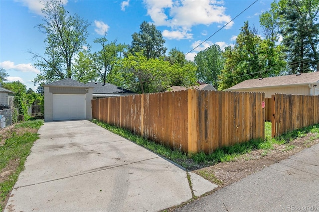1177 Wabash St, Denver, CO 80220 - view of side of property with fence, driveway, stucco siding, and a detached garage