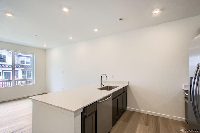 kitchen featuring a sink, light wood-type flooring, baseboards, a peninsula, and appliances with stainless steel finishes