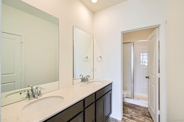 bathroom with double vanity, toilet, a stall shower, and a sink
