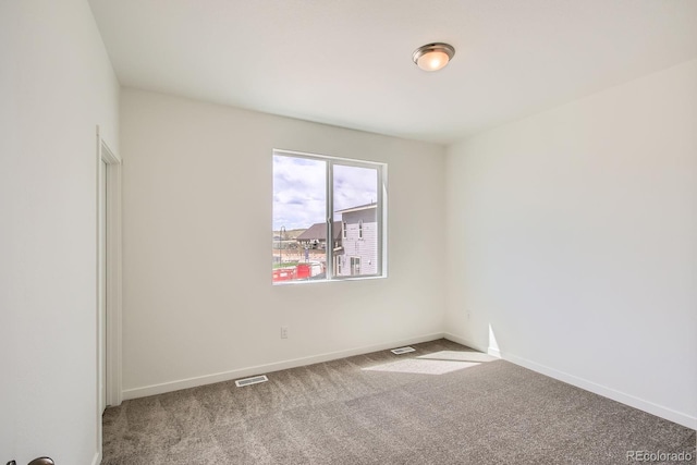 carpeted spare room with visible vents and baseboards