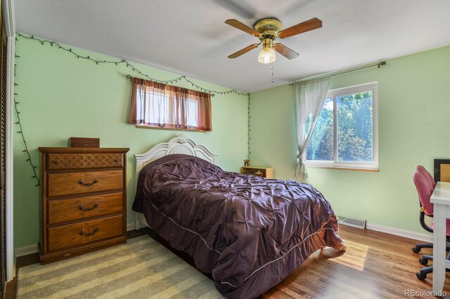 bedroom with ceiling fan, wood-type flooring, and multiple windows