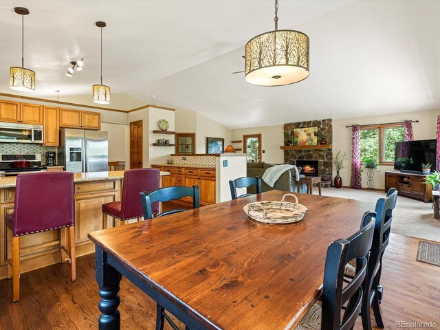 19795 Flint Ln, Morrison, CO 80465 - dining area with vaulted ceiling, plenty of natural light, a stone fireplace, and wood finished floors