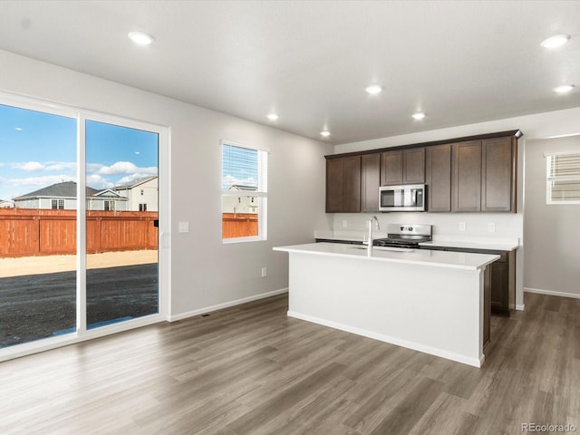 kitchen featuring dark wood-type flooring, dark brown cabinetry, sink, an island with sink, and stainless steel appliances