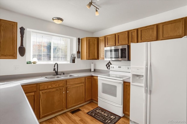 kitchen with light hardwood / wood-style flooring, rail lighting, sink, and white appliances