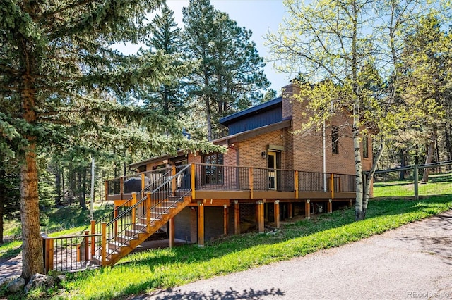 25357 Snyder Ave, Conifer, CO 80433 - back of property featuring a wooden deck, stairway, brick siding, and fence